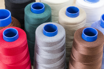 Several spools of thread of different colors and sizes on a wooden table
