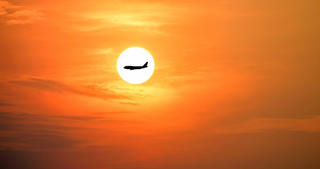 Closeup of the airplane silhouette on the beautiful sun and red sky.