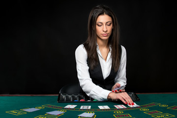 The beautiful girl, dealer, behind a table for poker