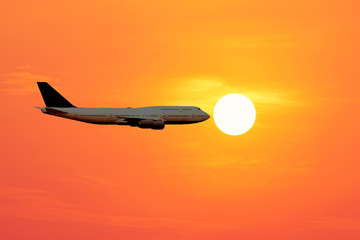 Naklejka na ściany i meble Closeup of the airplane silhouette on the beautiful sun and red sky.