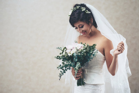 Joyful beautiful bride looking at her boquet