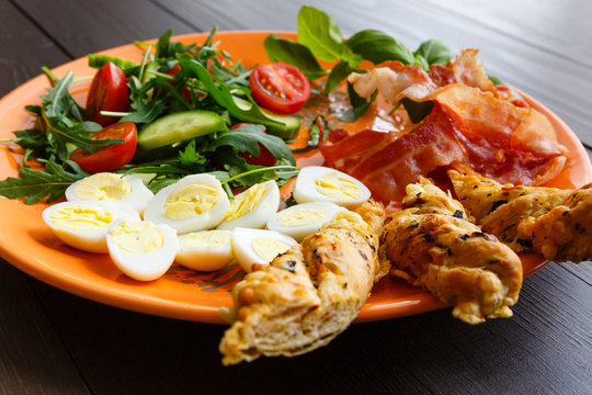 Closeup of boiled quail eggs with bacon and salad. Traditional english breakfast on old wooden boards