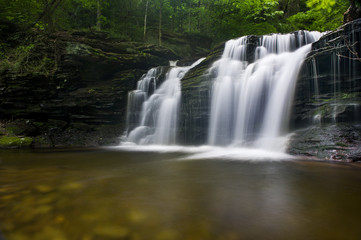 Fototapeta na wymiar A long exposure of a waterfall scene in a forest of green trees.