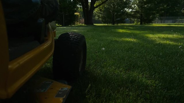 A suburban home owner mowing the grass with a tractor