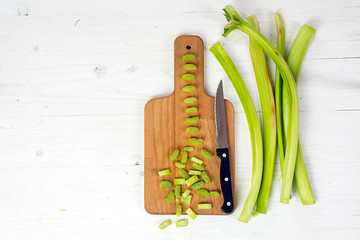 rhubarb stalks, slices and a kitchen knife on a cutting board from above