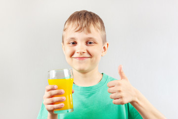 Little funny boy with a glass a fresh orange juice