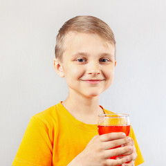 Little blonde boy with a glass of fresh red lemonade