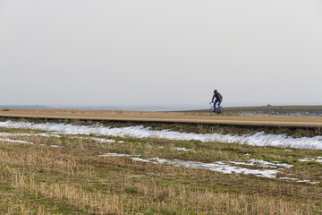 Fototapeta na wymiar Ciclista por carretera en paisaje invernal con nieve