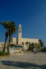Fototapeta na wymiar St. Peter's Church. The bell tower with clock of the Church. Sunset light in Jaffa, Israel