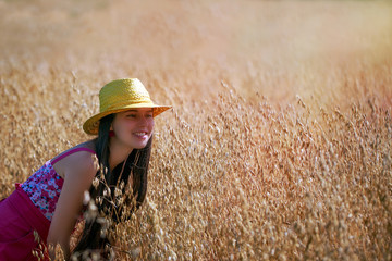 Young woman with hat standing on the oat field.