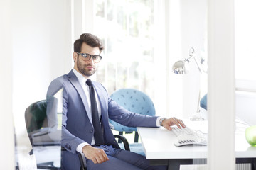 Portrait of confident financial professional man sitting in front of computer and working.