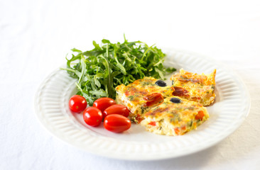 omelet on a white plate with salad and cherry tomatoes 