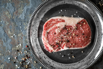 Piece of ribeye steak marble and peppercorn on a plate of tin