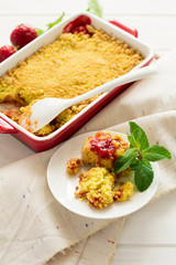 Homemade strawberry crumble on white wooden background