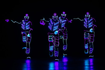 dancers in led suits on dark background, colored show