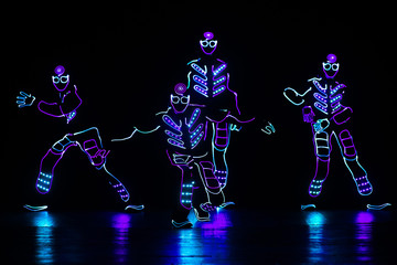 dancers in led suits on dark background, colored show