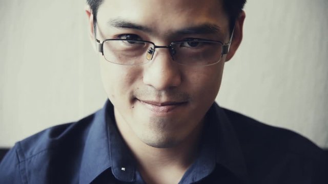 Portrait of Handsome Chinese-Thai  Asian male in dark blue shirt with smile face looking at camera  slow-motion