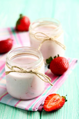 Strawberry yogurt in glass on a mint wooden table
