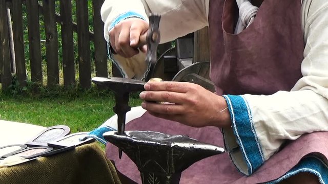 Man works with hammer and anvil coppersmith bracelet historical reconstruction amateur festival Kaleto, Mezdra, Bulgaria
