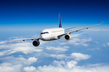 Naklejka na ściany i meble Commercial jet plane flying above clouds