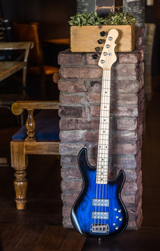 Bass Guitar Leaning Against Brick Wall. Blue Bass Guitar. Still Life with Bass Guitar.