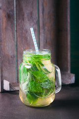 Tasty colorful drink with cold green tea, mint and cucumber in a glass jar on a vintage background, closeup