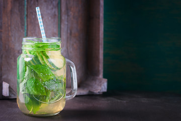 Tasty colorful drink with cold green tea, mint and cucumber in a glass jar on a vintage background, closeup, horizontal, with place for text