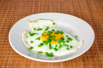 Fried egg in a white plate on a bamboo cover