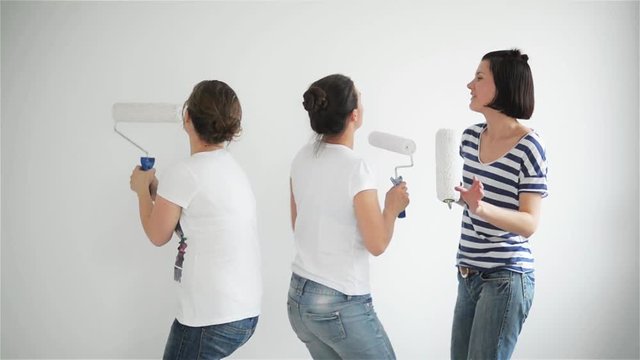 Friends makes repairs at home. Funny girls dance and paint the walls in the flat
