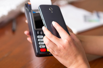 Close up of black mobile phone and credit card machine, code scan to pay the bill
