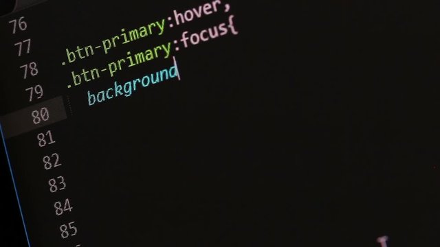 Closeup video of a freelancers computer screen while writing CSS code from scratch, in this case a default primary button and a transparent button style.