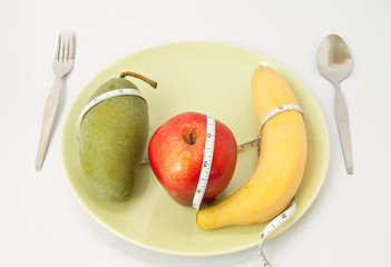 Diet concept. Fruits and vitamins with measuring tape on a dish
