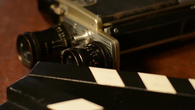 Close-up reel of film and vintage camera with two lenses. Clapper for movie filming