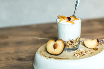 glass of granola, cereal, yogurt with peach and plum