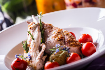 Grilled rabbit leg with rosemary and vegetable decoration.