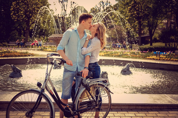 A man his girlfriend near fountain in a park.