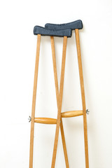 Wooden crutches rest on white wall
