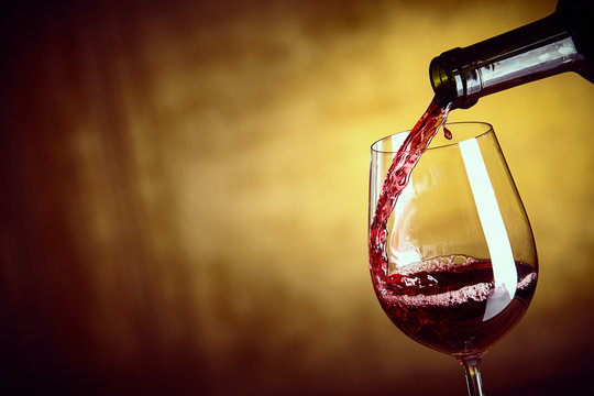 Fototapeta Pouring a single glass of red wine from a bottle