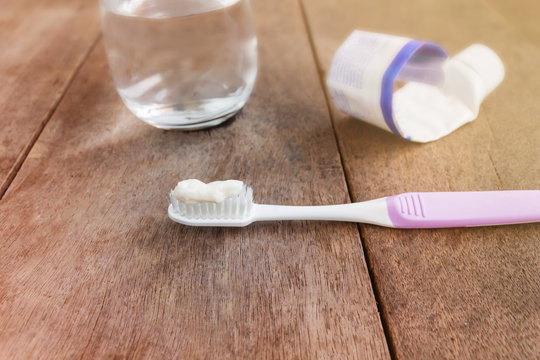 Toothbrush with toothpaste on blurred glass of water background, simply daily morning , economic or save behaviour concept, run put of toothpaste