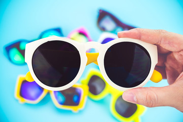 hand holding sunglasses with blur group of glasses at background