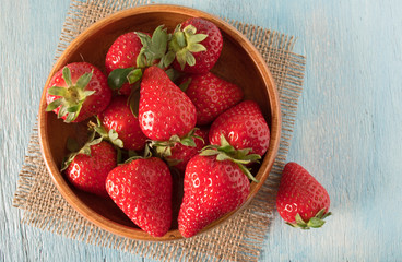 Strawberries in bowl on wooden background