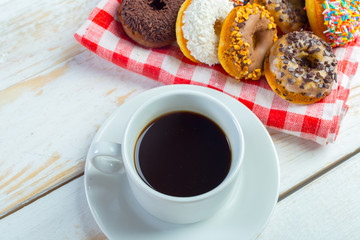 Donuts and coffee on a white wood background.