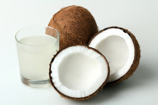 halves of coconut with glass of coconut milk on a white isolated background