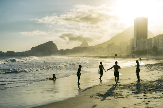 Beach football altinho silhouettes playing in the waves on the sunset shore of Copacabana Beach at sunset in Rio de Janeiro, Brazil 