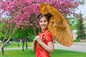 Beautiful asian girl in traditional chinese red dress with bamboo umbrella.