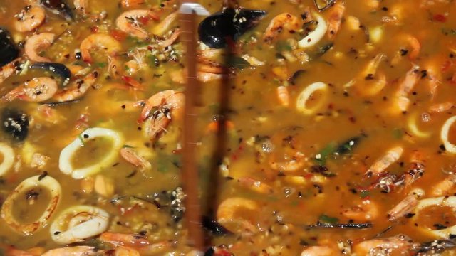 Removiendo con una espumadera la paella de marisco con caldo