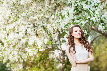 Young beautiful girl posing near apple-tree in blossom