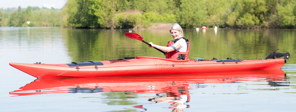 junge frau paddelt mit dem kajak auf einem fluss