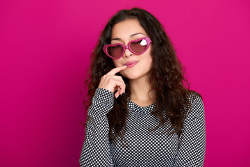 young woman beautiful portrait, posing on pink background, long curly hair, sunglasses in heart shape, glamour concept