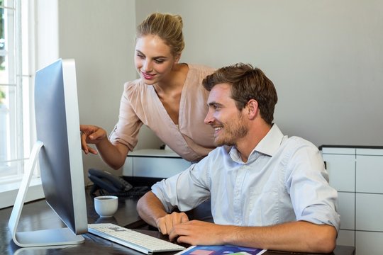 Female colleague pointing on computer at office